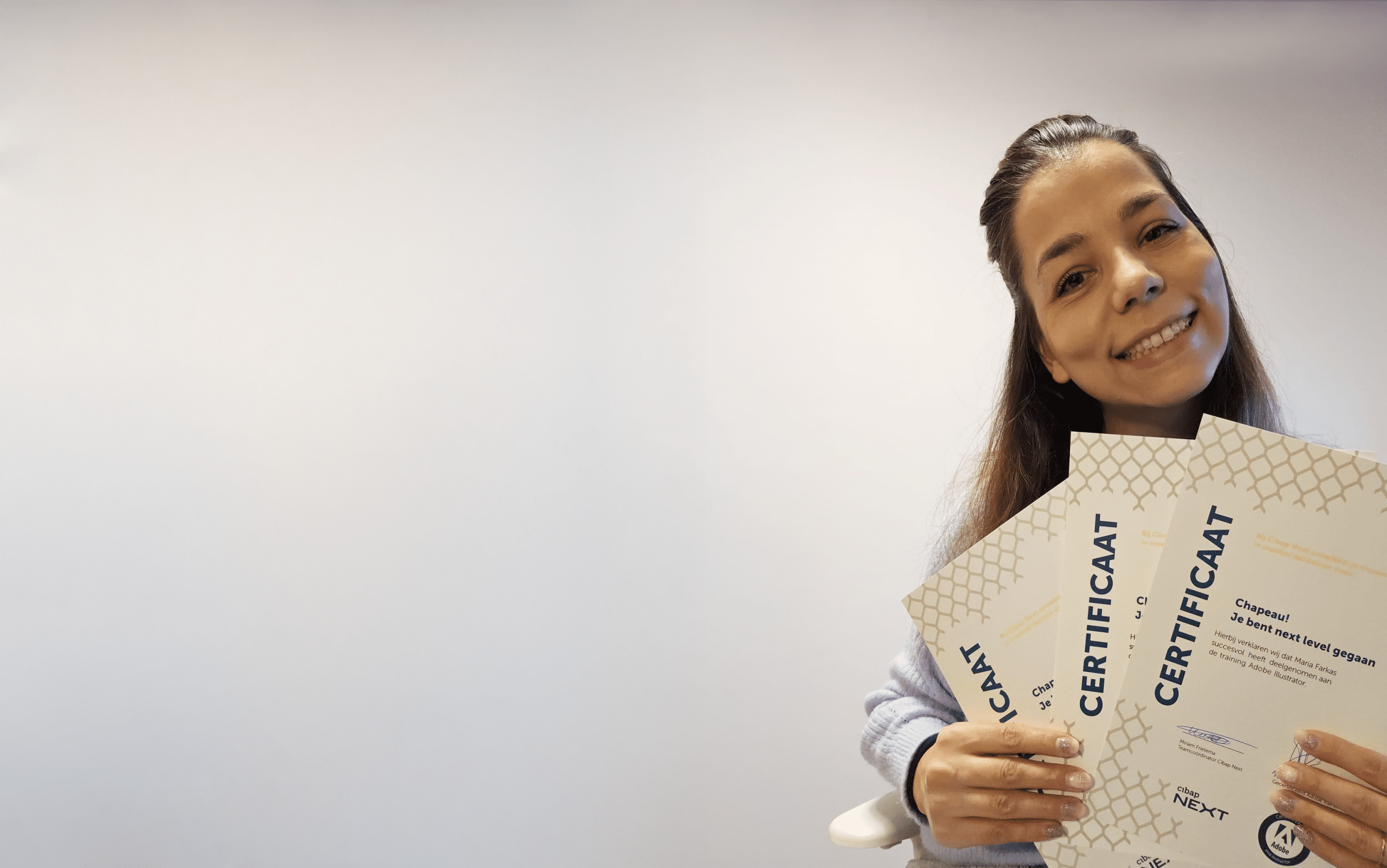 Vrouw poseert met drie certificaten van Cibap Next van de trainingen Adobe InDesign, Adobe Photoshop en Adobe Illustrator